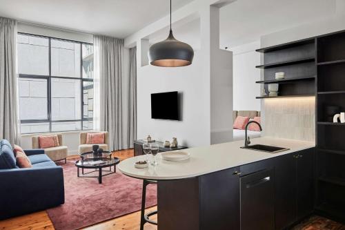a kitchen with a table and a living room at Adina Apartment Hotel Melbourne Flinders Street in Melbourne