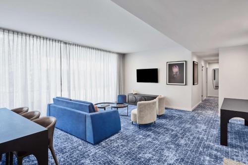 a living room with blue furniture and a piano at Adina Apartment Hotel Melbourne Flinders Street in Melbourne
