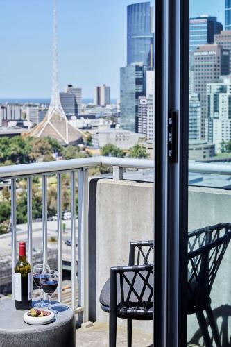 a glass of wine sitting on a table on a balcony at Adina Apartment Hotel Melbourne Flinders Street in Melbourne