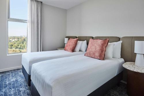 two beds in a hotel room with a window at Adina Apartment Hotel Melbourne Flinders Street in Melbourne
