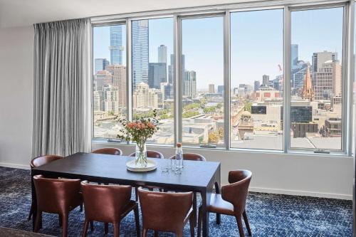 a dining room with a table and chairs and a large window at Adina Apartment Hotel Melbourne Flinders Street in Melbourne