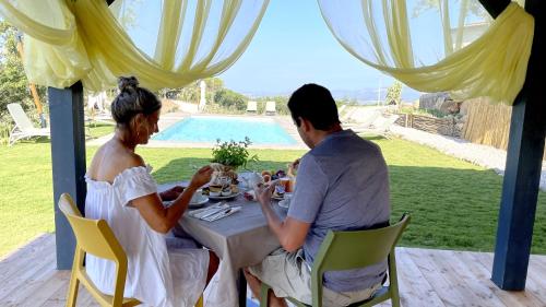 Ein Mann und eine Frau sitzen an einem Tisch unter einem Zelt in der Unterkunft Poggio Belvento in Suvereto
