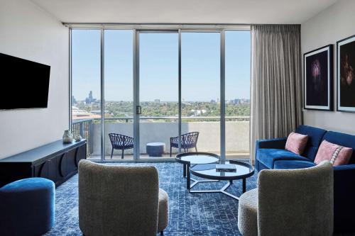 a living room with a couch and chairs and a tv at Adina Apartment Hotel Melbourne Flinders Street in Melbourne