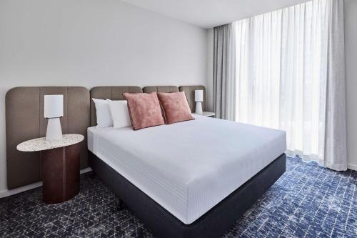 a bedroom with a large white bed and a window at Adina Apartment Hotel Melbourne Flinders Street in Melbourne