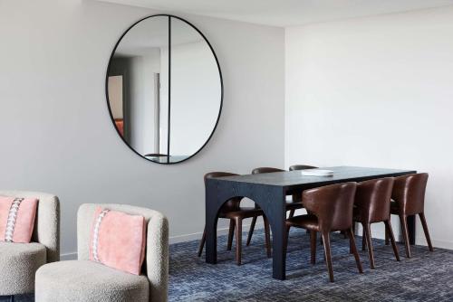a dining room with a table and chairs and a mirror at Adina Apartment Hotel Melbourne Flinders Street in Melbourne