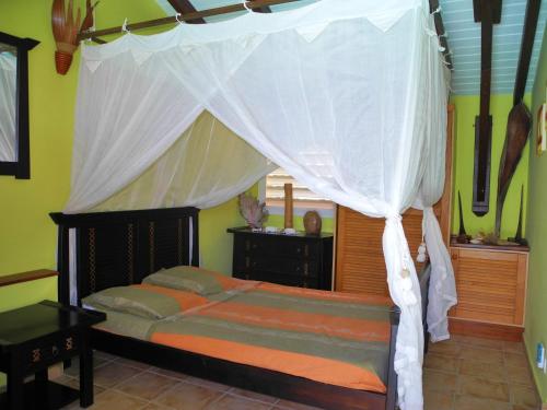 a bedroom with a bed with a canopy at Villa grand bleu in Sainte-Rose