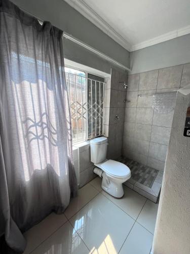 a bathroom with a toilet and a window at Sherotha Accommodation in Louis Trichardt