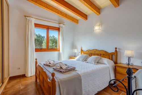 a bedroom with a bed with white sheets and a window at Chalet Turó in Cala Santanyi