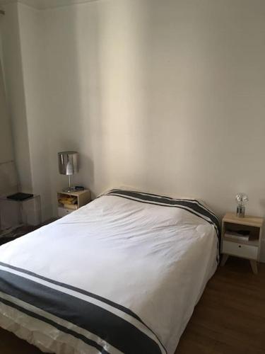 - un lit blanc dans une chambre avec deux tables dans l'établissement Roland Garros /Boulogne Billancourt, à Boulogne-Billancourt