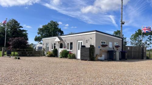 a small white house with a fence and a flag at Runway Cottage in Coningsby