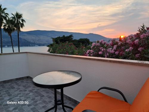 a table and chair on a balcony with a view of the water at Guest House Topla in Herceg-Novi