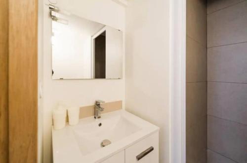 une salle de bain blanche avec un lavabo et un miroir dans l'établissement Sur Rbnb - Heros, à Marseille