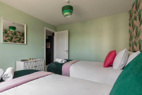 two beds in a room with white and green at Weekly & Monthly Rates! Stunning Home By Stansted Airport in Bishops Stortford