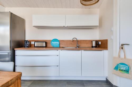 a kitchen with white cabinets and a sink at L'Épine - Maison lumineuse - 300m de la plage in LʼÉpine