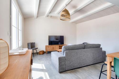 a living room with a couch and a tv at L'Épine - Maison lumineuse - 300m de la plage in LʼÉpine