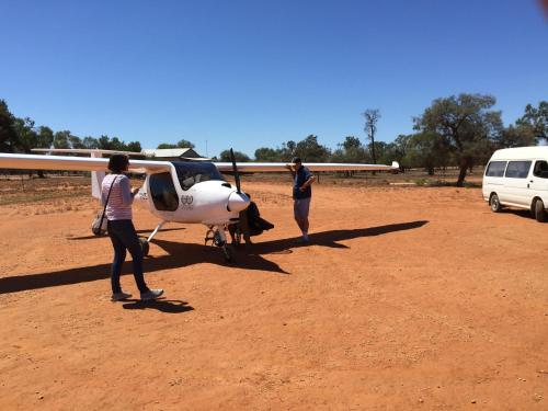 
a man standing on top of a dirt field next to an airplane at Mungo Lodge in Mungo
