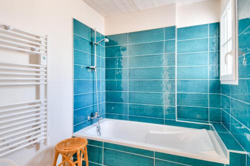 ein blau gefliestes Bad mit einer Badewanne und einem Stuhl in der Unterkunft Echapee familiale a l Epine in LʼÉpine
