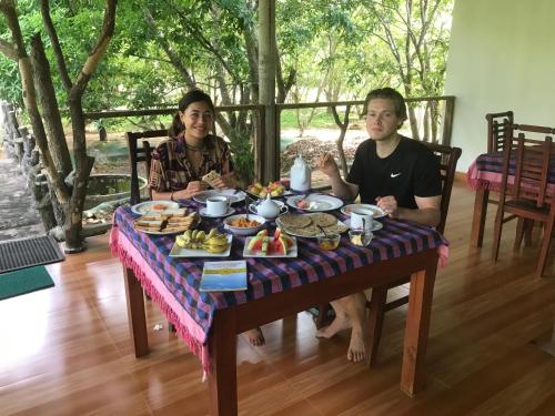 two people sitting at a table with food on it at Darshani Lodge in Sigiriya