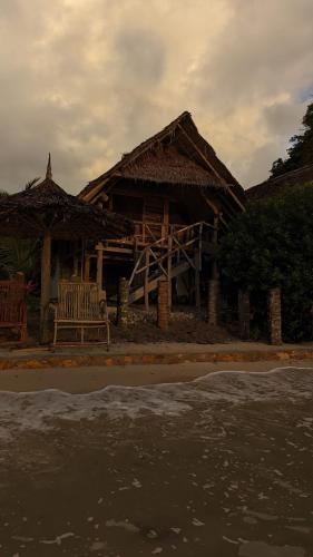 a house with two chairs in front of the ocean at Mawe Mawili in Tanga