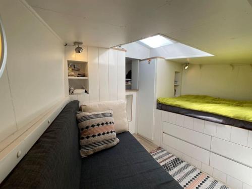 Spacious homely house boat في أمستردام: غرفة صغيرة مع أريكة وسرير