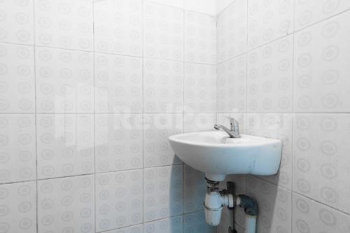 a bathroom with a sink in a white tiled wall at Teratai Guesthouse at RS Adam Malik Medan Mitra RedDoorz in Medan
