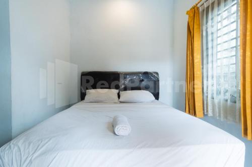 una camera da letto con un grande letto bianco e una finestra di Teratai Guesthouse at RS Adam Malik Medan Mitra RedDoorz a Medan