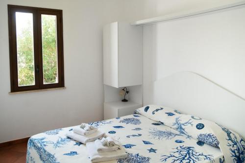 カステッランマーレ・デル・ゴルフォにあるN'amuri Villasのベッドルーム1室(青と白のシーツが敷かれたベッド1台、窓付)