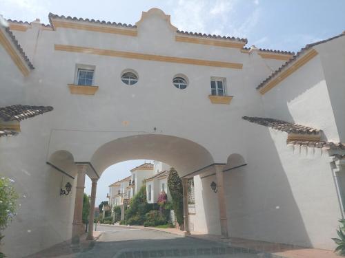a white building with an archway in a street at Moraleja, habitación en bajos con jardín en Estepona in Estepona