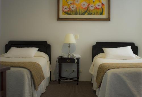 Habitación con 2 camas y una lámpara en una mesa. en Hotel Las Terrazas Express en Chillán