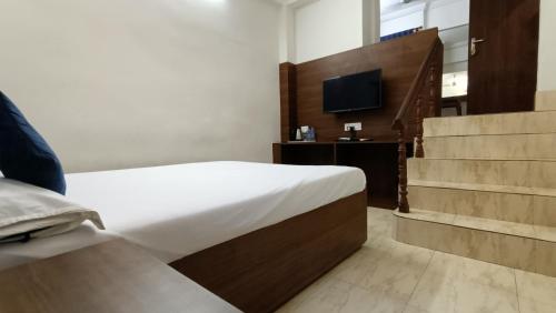 a bedroom with a bed and a tv and stairs at Hotel Saluja in Siliguri