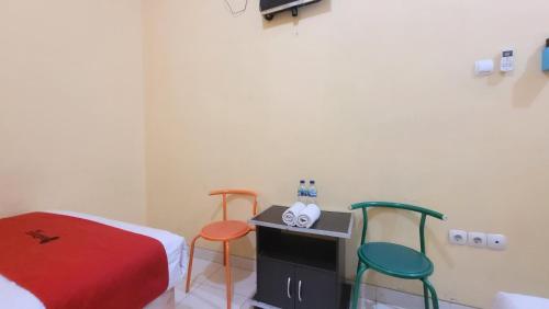 a room with two chairs and a bed and a table at RedDoorz Syariah At Endrayanti Inn RSUD Yogyakarta in Timuran