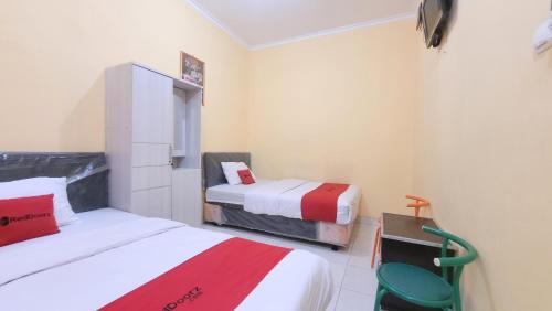 a room with two beds and a chair in it at RedDoorz Syariah At Endrayanti Inn RSUD Yogyakarta in Timuran