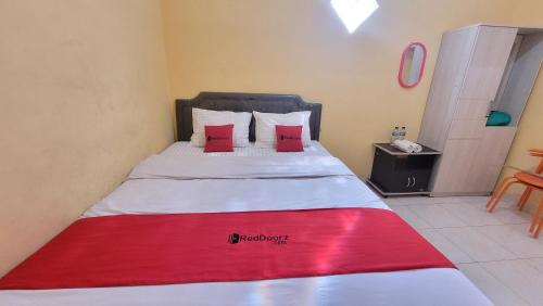 a bedroom with a bed with a red blanket on it at RedDoorz Syariah At Endrayanti Inn RSUD Yogyakarta in Timuran