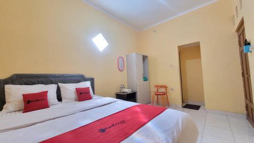a bedroom with a large bed with red pillows at RedDoorz Syariah At Endrayanti Inn RSUD Yogyakarta in Timuran