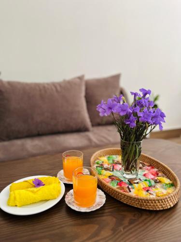 a table with two plates and two glasses of orange juice at Kemi House Hoi An in Hoi An