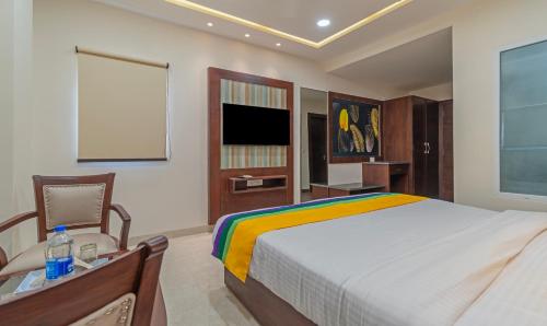a bedroom with a bed and a chair and a television at Itsy Hotels P Grand in Ludhiana