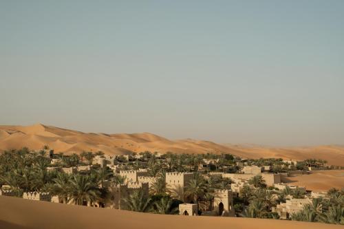 a city in the desert with palm trees and buildings at Anantara Qasr al Sarab Desert Resort in Jurayrah