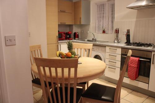 a kitchen with a wooden table with a bowl of fruit on it at Eldridge Court Apartment in Dagenham