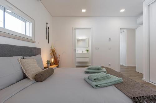 ein weißes Schlafzimmer mit einem großen Bett mit Handtüchern darauf in der Unterkunft Your Peace & Quiet, close to the Silver Coast in Lourinhã