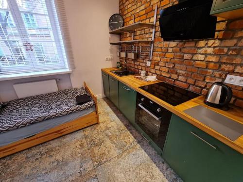 a kitchen with a bed and a brick wall at Fantastic Apartments - KP69 Room - A in Warsaw