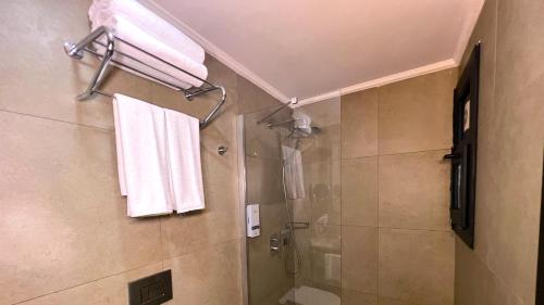 a bathroom with a shower and a toilet and towels at Crown Salamis Hotel in Mağusa