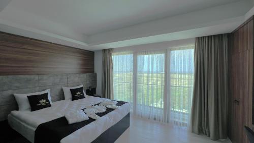 a bedroom with a large bed and large windows at Crown Salamis Hotel in Famagusta