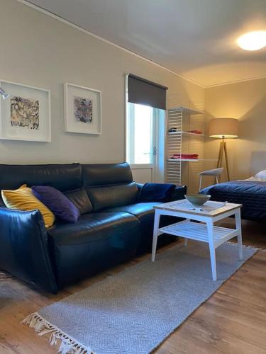 a living room with a black leather couch and a table at ABONNERA Lugnt centralt parkering altan in Växjö
