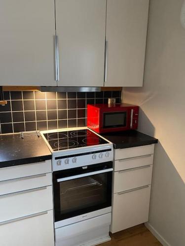 a kitchen with a stove and a red microwave at ABONNERA Lugnt centralt parkering altan in Växjö