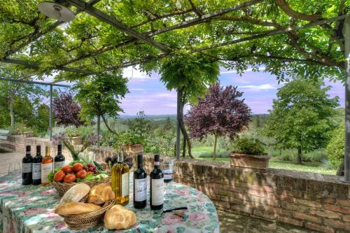 uma mesa com garrafas de vinho e uma cesta de frutas em allegretti agriturismo em Castelnuovo Berardenga