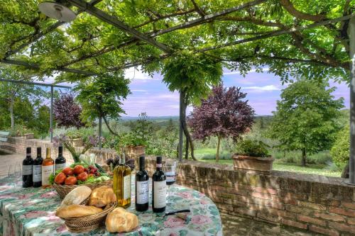 un tavolo con bottiglie di vino e un cesto di frutta di allegretti agriturismo a Castelnuovo Berardenga