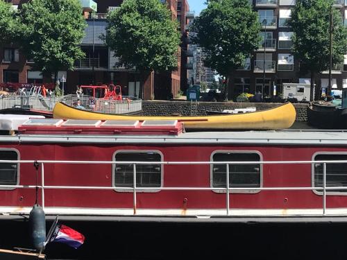 a red train with a yellow canoe on top of it at Spacious homely house boat in Amsterdam