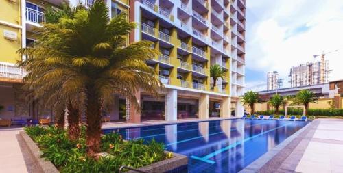 a swimming pool with a palm tree next to a building at Casa Concha by Celandine private residences in Manila