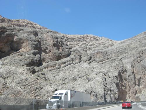 a semi truck driving down a road next to a mountain at Nevada Mesquite Vacation Rentals in Mesquite