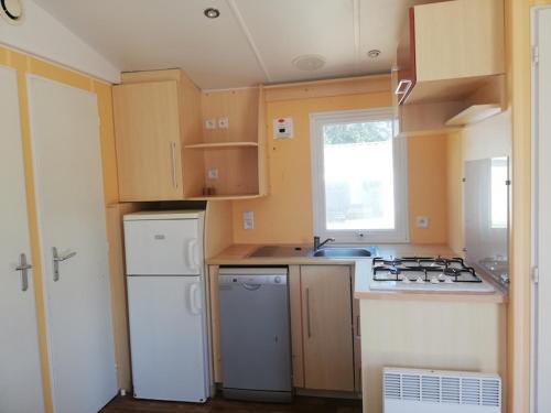 een kleine keuken met witte apparatuur en een raam bij Hébergements sur camping au bord de la mer in Crozon